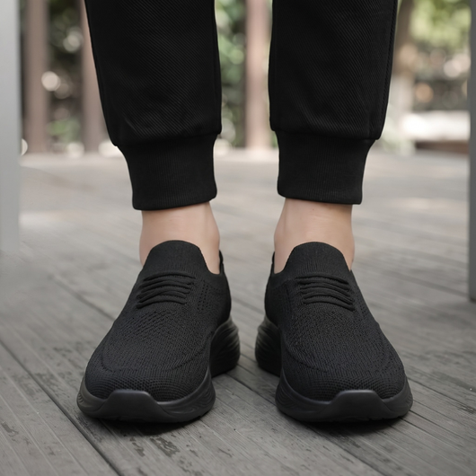 Svarte slip-on komfortsko unisex brukt utendørs på tredekk, sett forfra