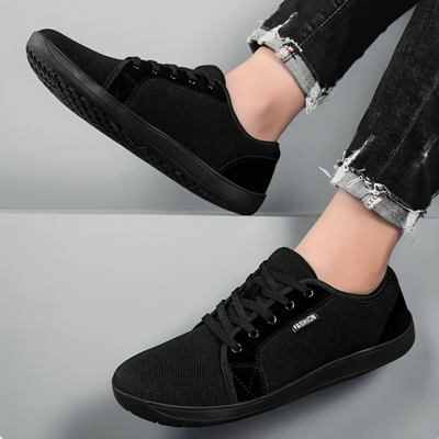 Svart minimalistisk barfotsko sett fra siden og ovenfra, brukt med svarte jeans