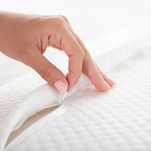 Nærbilde av hånd som åpner glidelåsen på det avtakbare putetrekket på ergonomisk pute