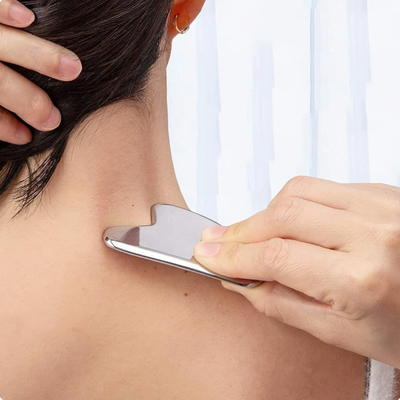En kvinne bruker en Gua Sha-massasjeskrape på nakken og skuldrene
