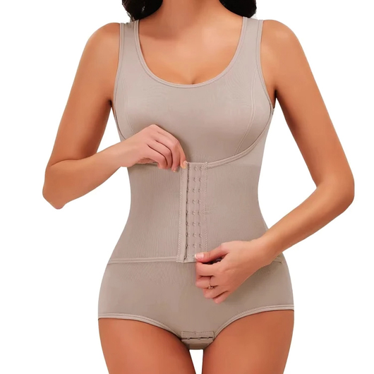 Kvinne knapper korsettdelen på en beige formende body, nærbilde av midjen